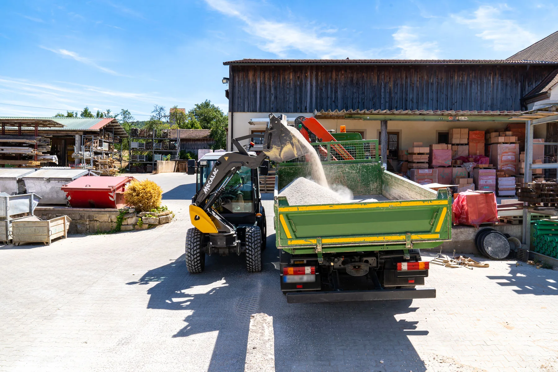 Mecalac AS600 Schwenklader belädt einen Lkw mit Schüttgut