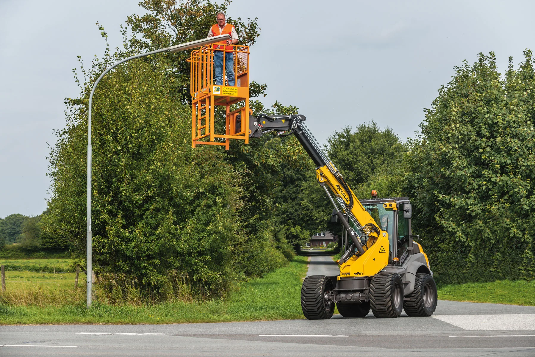 Mecalac AS900tele Schwenklader hebt eine Arbeitsplattform an einer Straßenleuchte