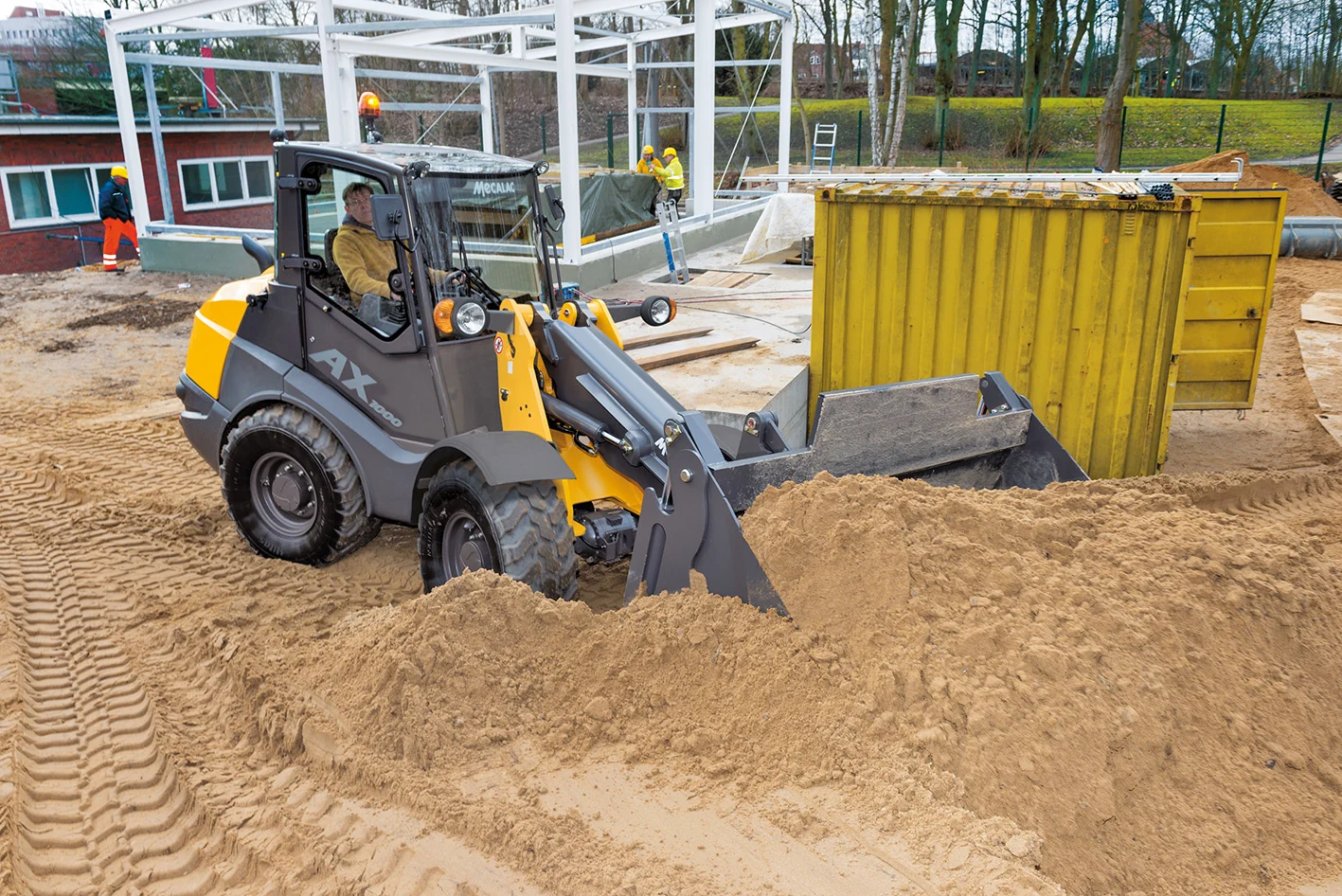 Mecalac AX1000 Radlader lädt Sand auf einer Baustelle