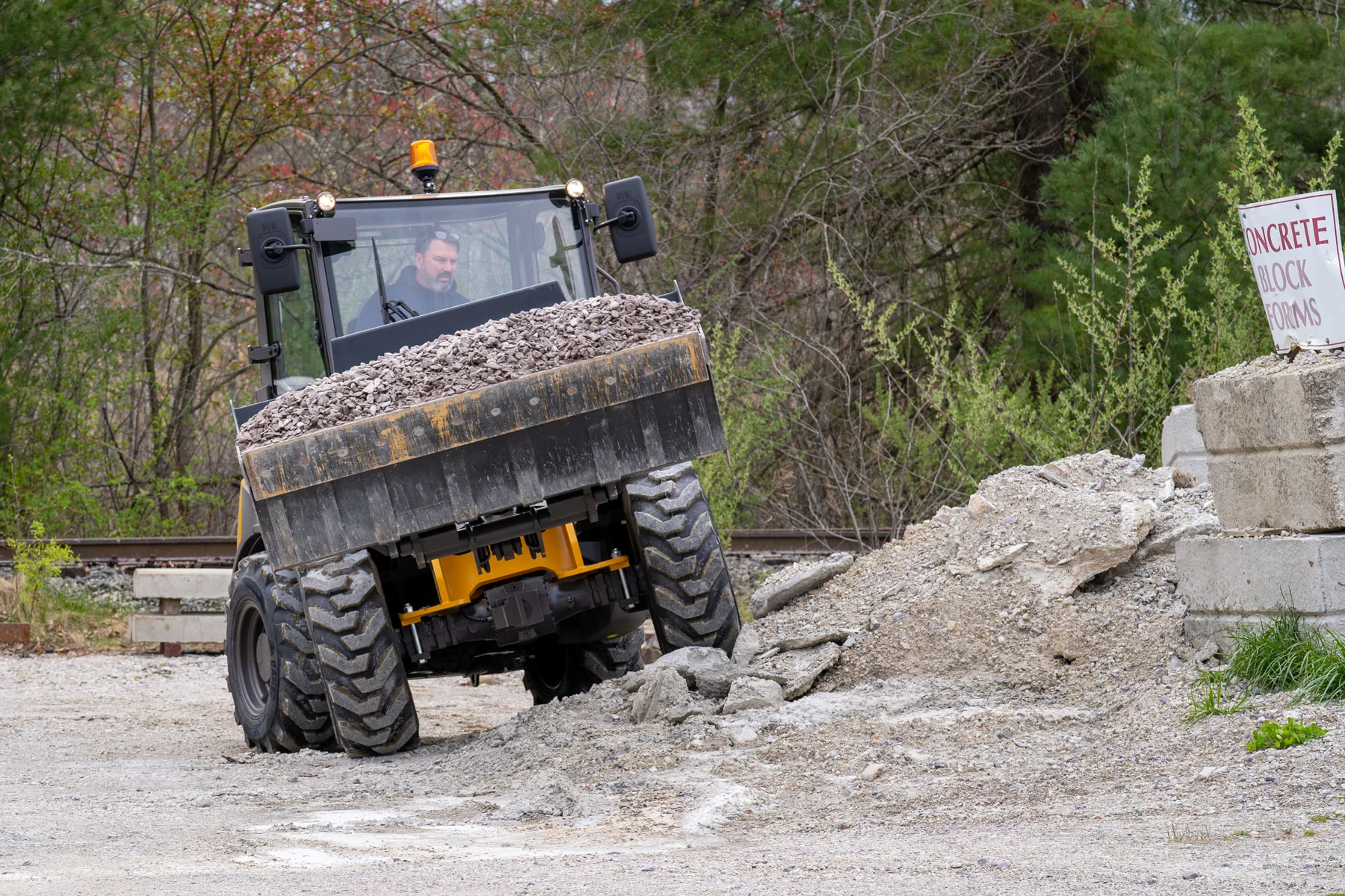Mecalac AX850 Radlader fährt mit gefüllter Schaufel über unebenes Baustellengelände