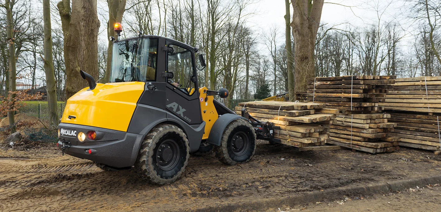 Mecalac AX850 Radlader transportiert gebündeltes Bauholz