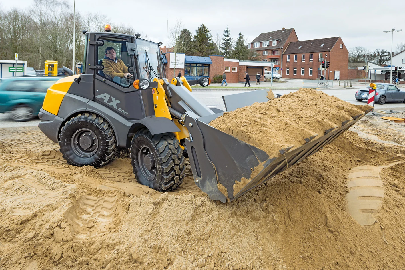 Mecalac AX850 Radlader nimmt Sand mit einer breiten Schaufel auf