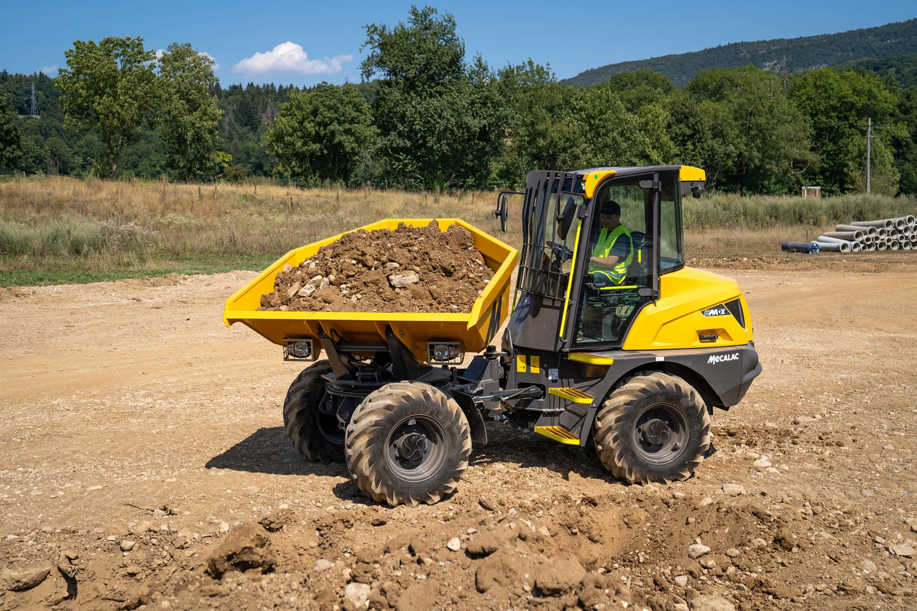 Mecalac 6MDX transportiert Aushub auf unebenem Gelände
