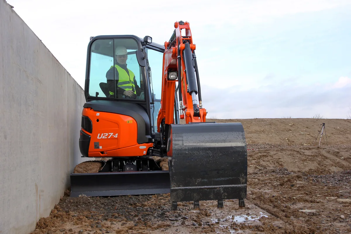 Kubota U27-4 mit Löffel bei Arbeiten entlang einer Mauer