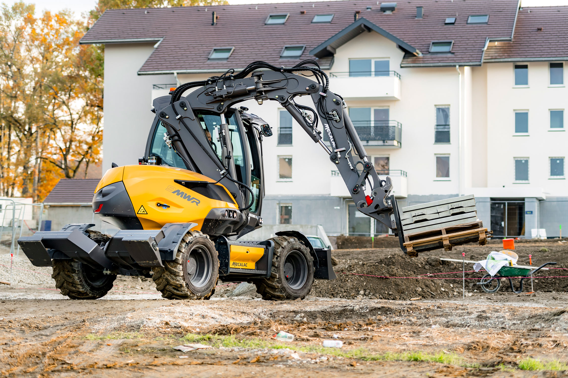 Mecalac 9MWR beim Transport von Paletten auf einer Baustelle