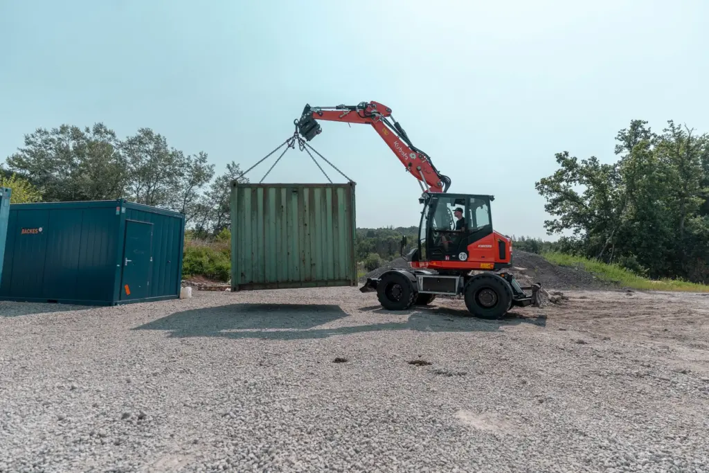 Kubota KW095 Mobilbagger hebt einen Baustellencontainer